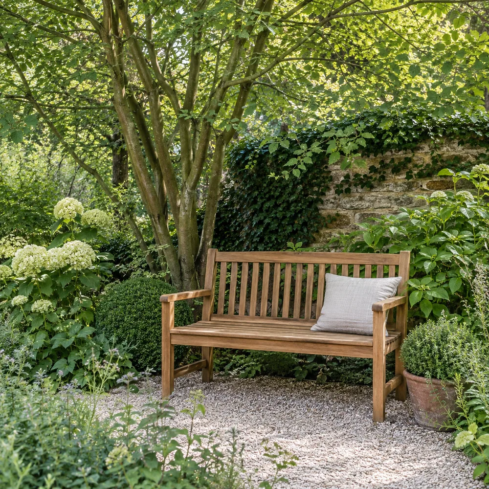 Banc en bois sous un arbre, entouré de feuillages et de fleurs blanches